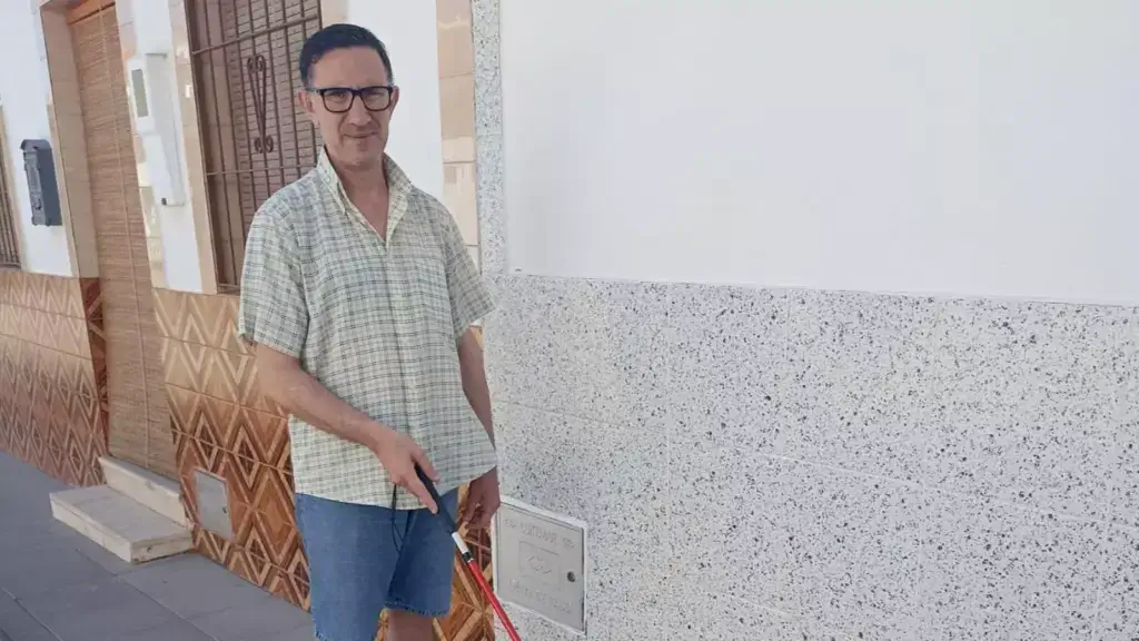 Andrés, posa en la calle. En su mano lleva el bastón rojo y blanco
