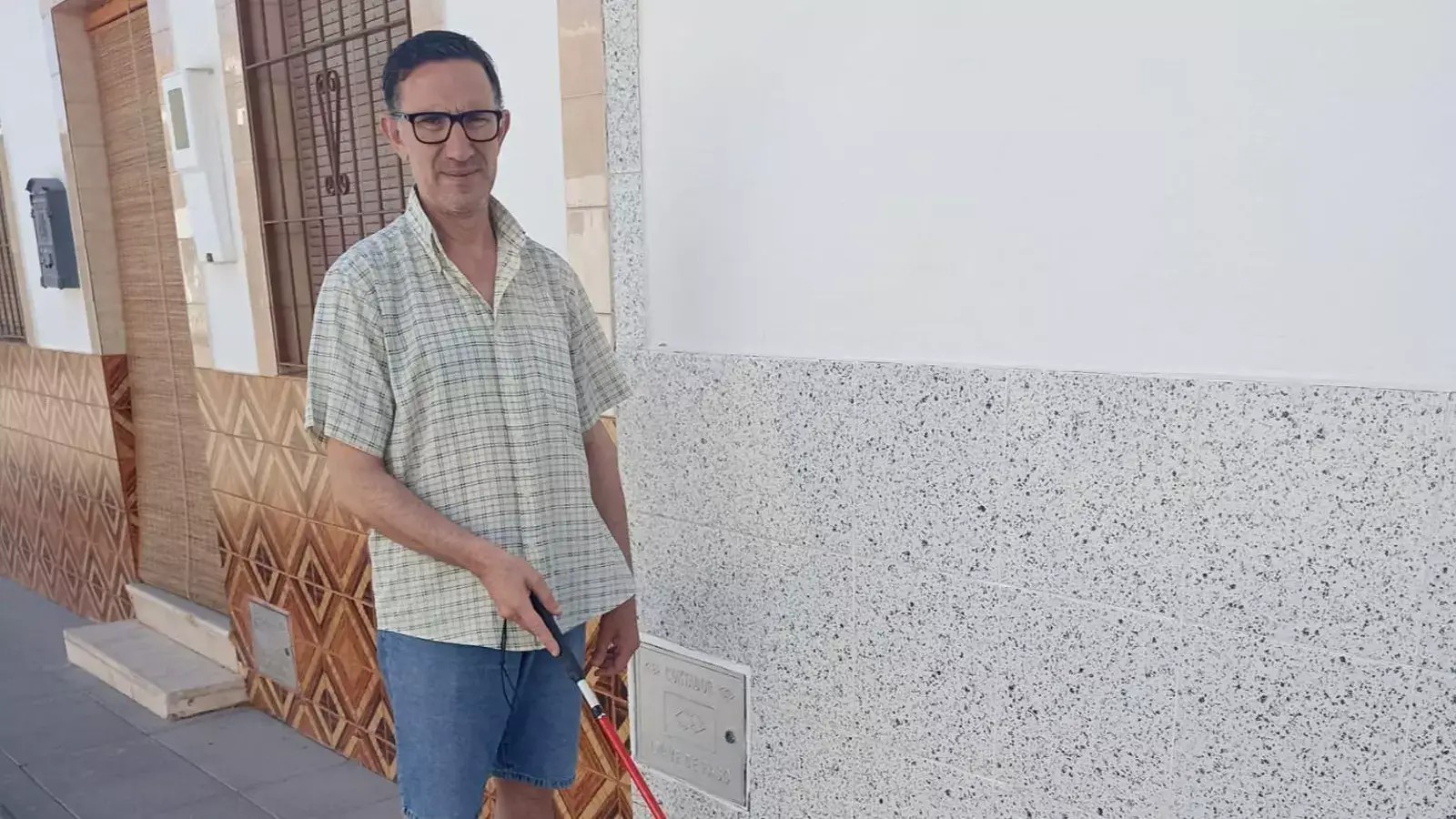 Andrés, posa en la calle. En su mano lleva el bastón rojo y blanco